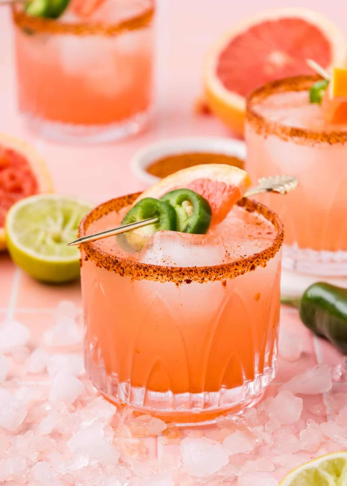 A grapefruit margarita garnished with jalapeno wheels and a slice of grapefruit.