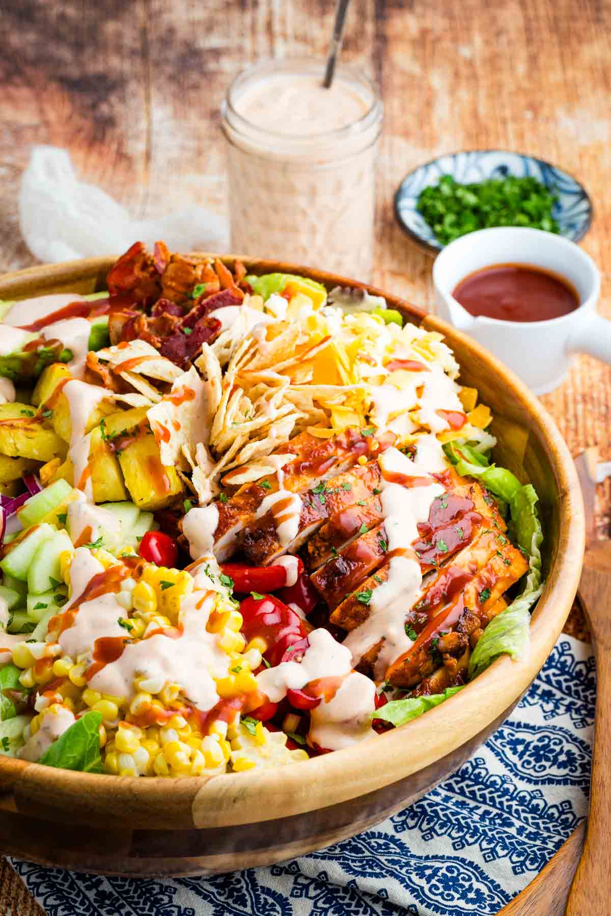 This BBQ chicken salad is loaded with BBQ chicken, crispy bacon, juicy pineapple, creamy avocado, and more. A sweet and savory masterpiece. The best BBQ chicken and pineapple salad in a wooden salad bowl.