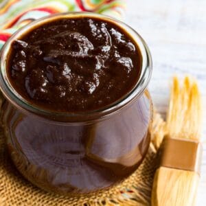 A jar of balsamic barbecue sauce with a brush next to it.