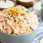 Buffalo chicken salad in a bowl, topped with tiny carrot and celery sticks.