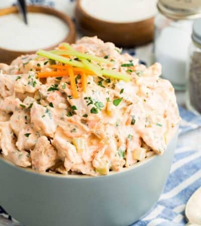 Buffalo chicken salad in a bowl, topped with tiny carrot and celery sticks.
