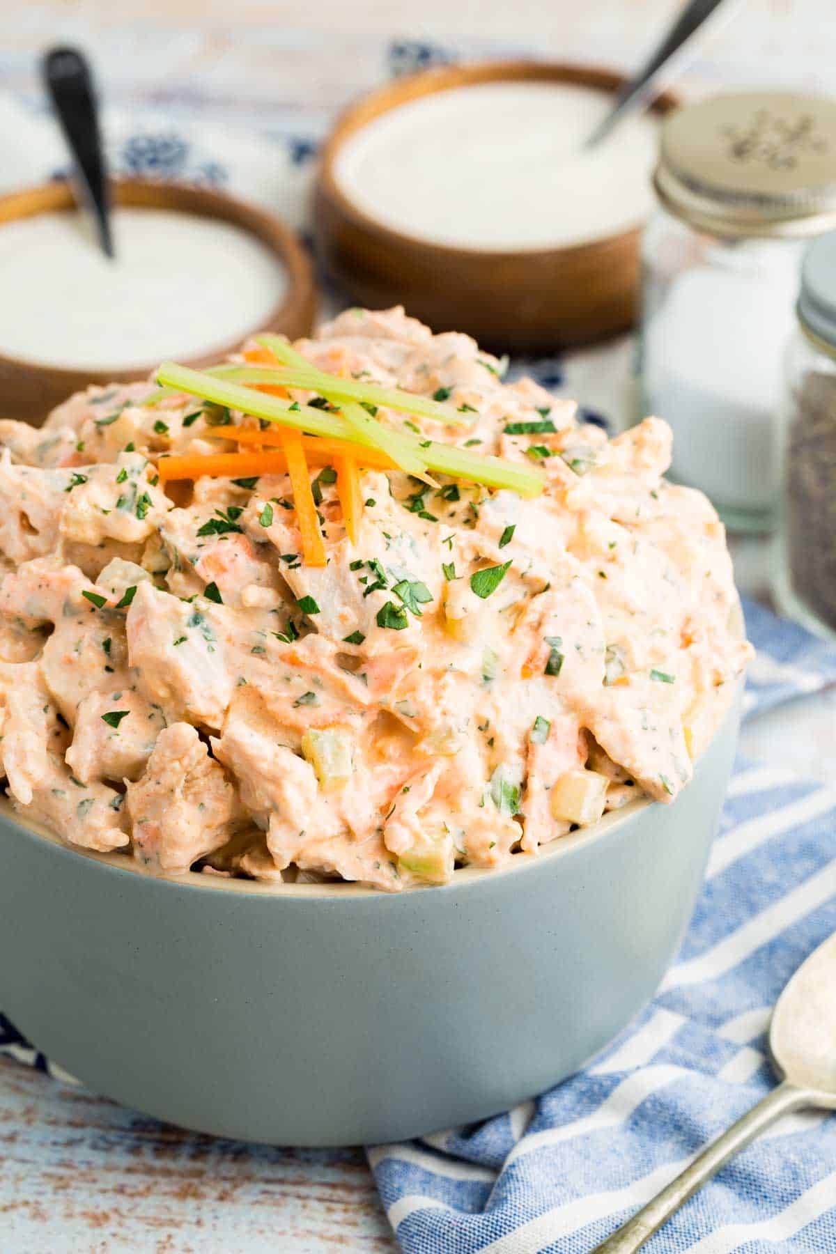 This flavor-packed Buffalo Chicken Salad is made with bold Greek yogurt dressing, tender chicken, crunchy veggies, and blue cheese. Yum! Buffalo chicken salad in a bowl, topped with tiny carrot and celery sticks.