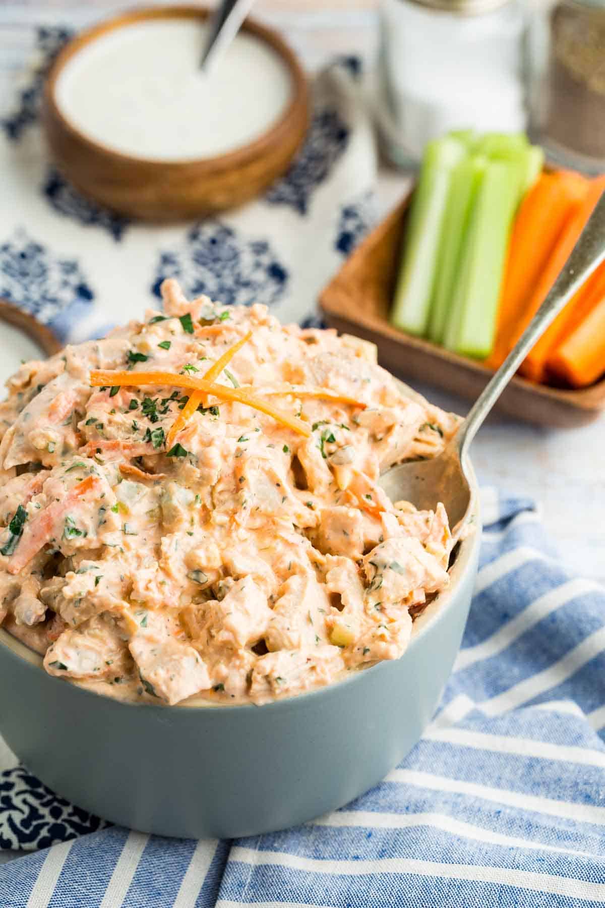 This flavor-packed Buffalo Chicken Salad is made with bold Greek yogurt dressing, tender chicken, crunchy veggies, and blue cheese. Yum! Buffalo chicken salad in a bowl with a spoon.