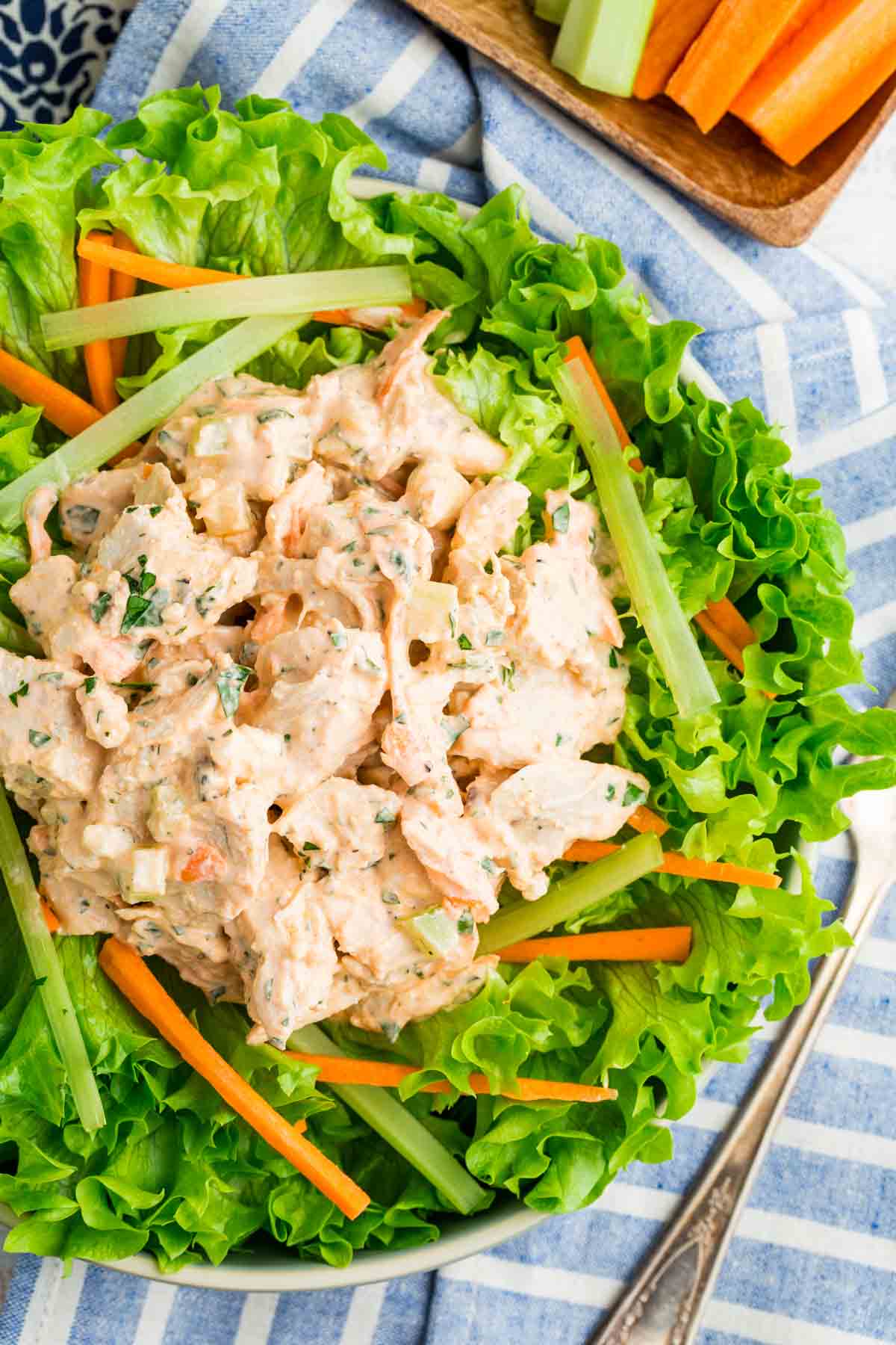 This flavor-packed Buffalo Chicken Salad is made with bold Greek yogurt dressing, tender chicken, crunchy veggies, and blue cheese. Yum! Overhead image of buffalo chicken salad over lettuce.