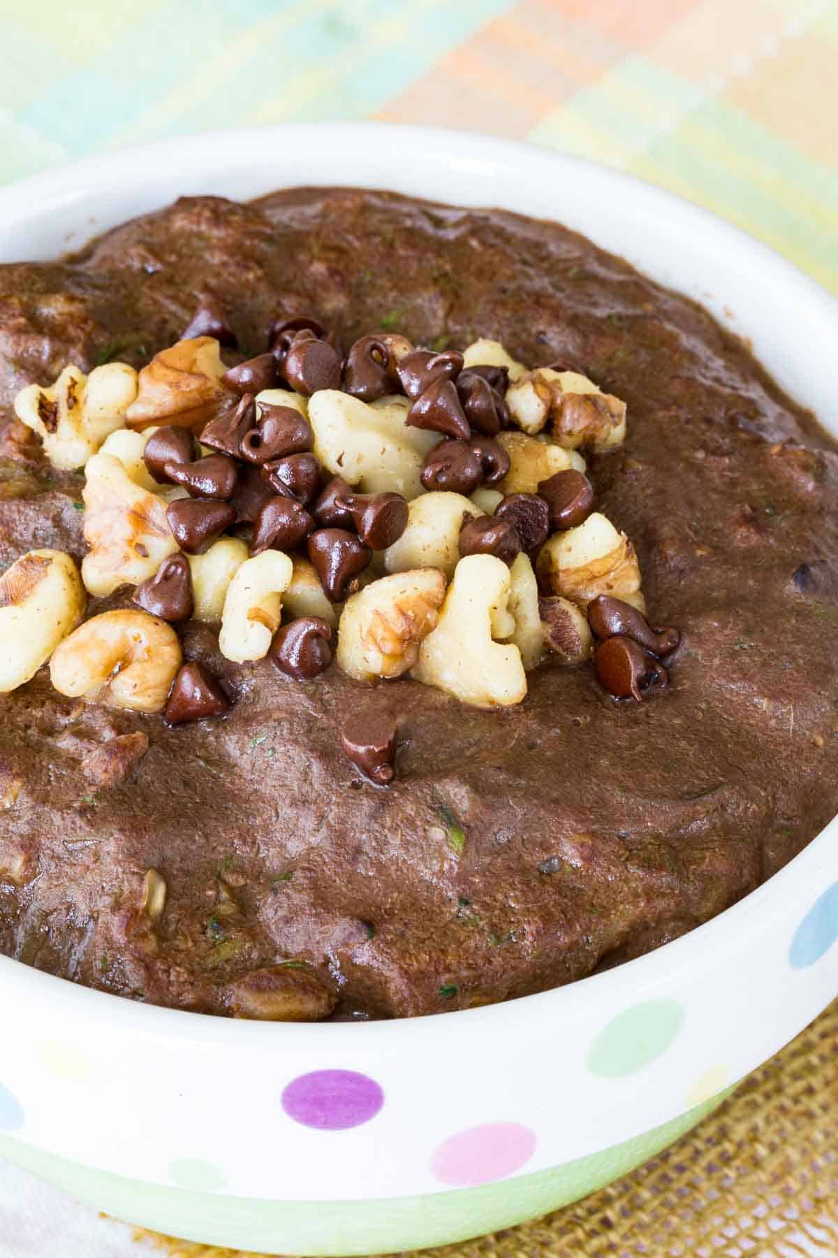 A closeup of chocolate zucchini oatmeal topped with walnuts and chocolate chips.