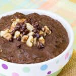 Chocolate oatmeal with walnuts and chocolate chips on top in a bowl on top of a placemat.