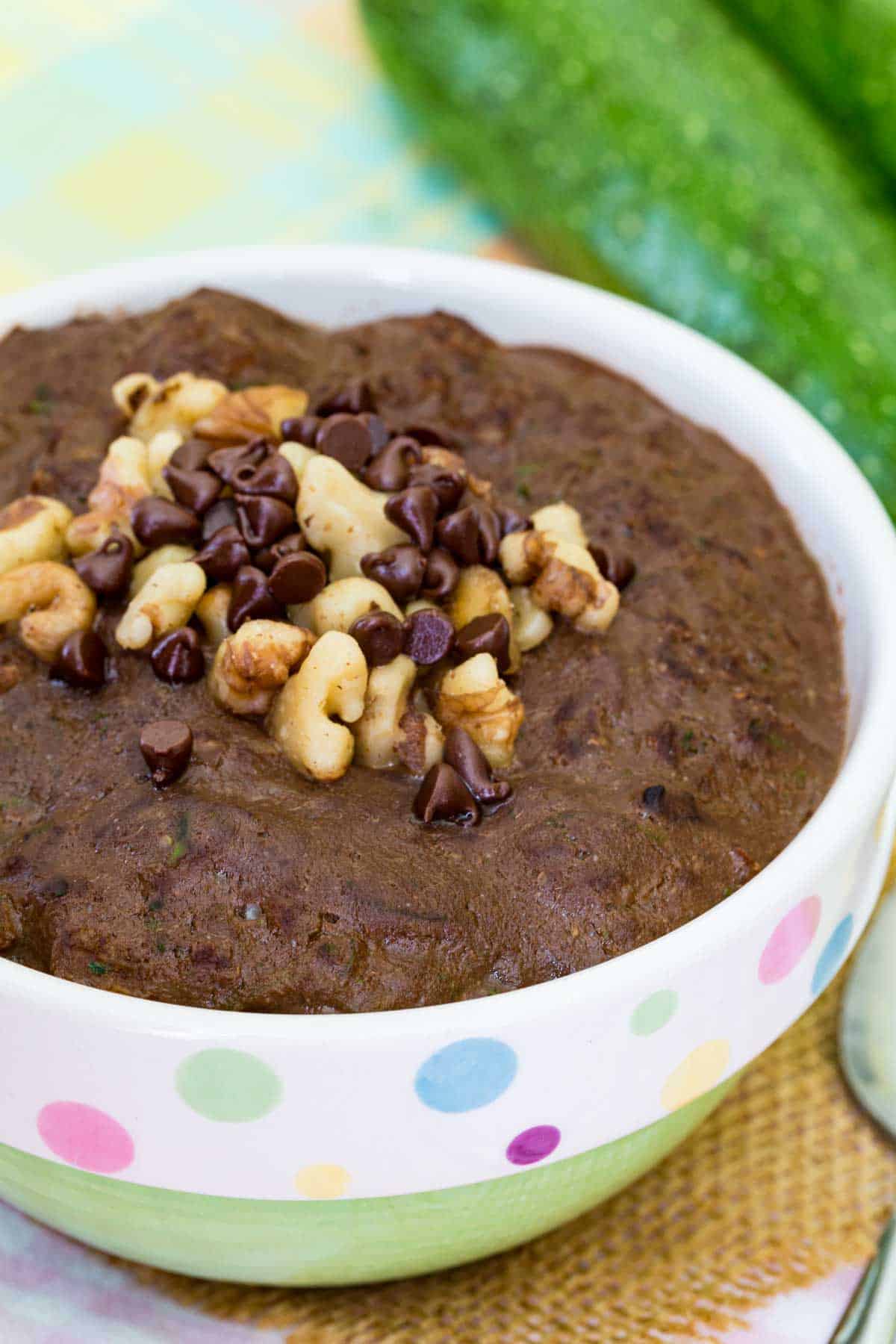 A bowl of chocolate zucchini oatmeal topped with walnuts and chocolate chips.