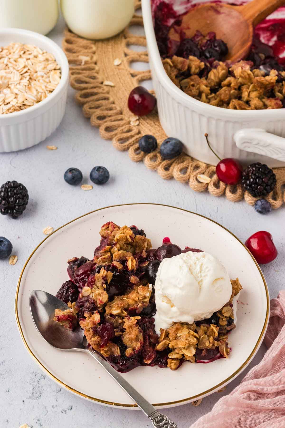 A plate of gluten-free berry crisp with ice cream on top and a spoon ready to dive in.
