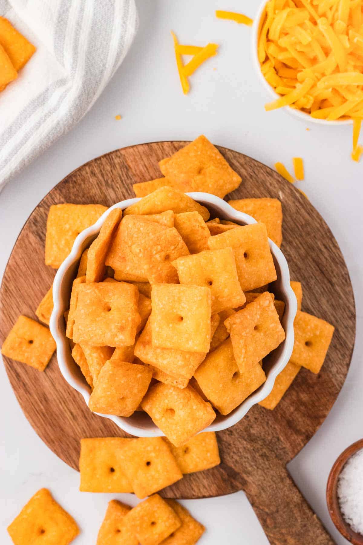 A hand holding a gluten-free cheddar cracker up to the camera.