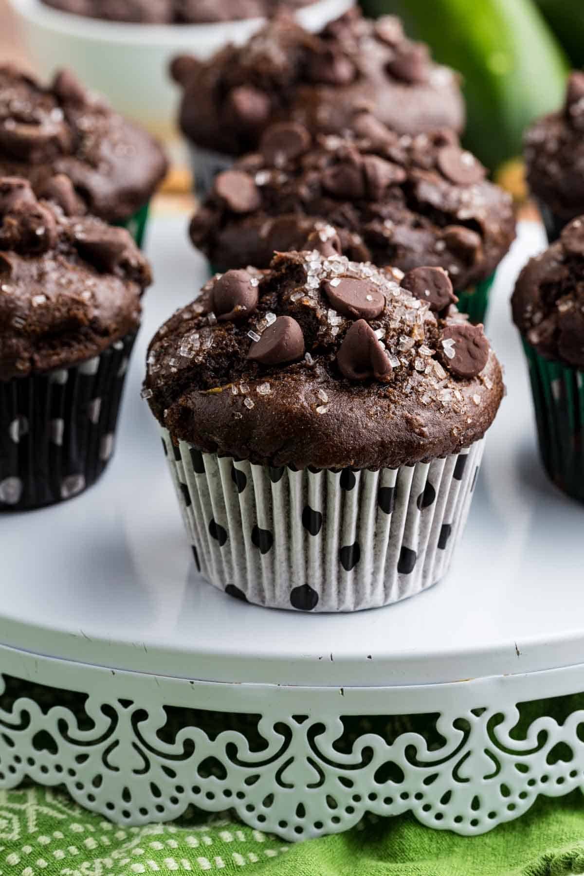 These gluten-free chocolate zucchini muffins are packed with melty chocolate chips and incredibly moist and tender, thanks to the zucchini. Chocolate zucchini muffins on a serving platform.