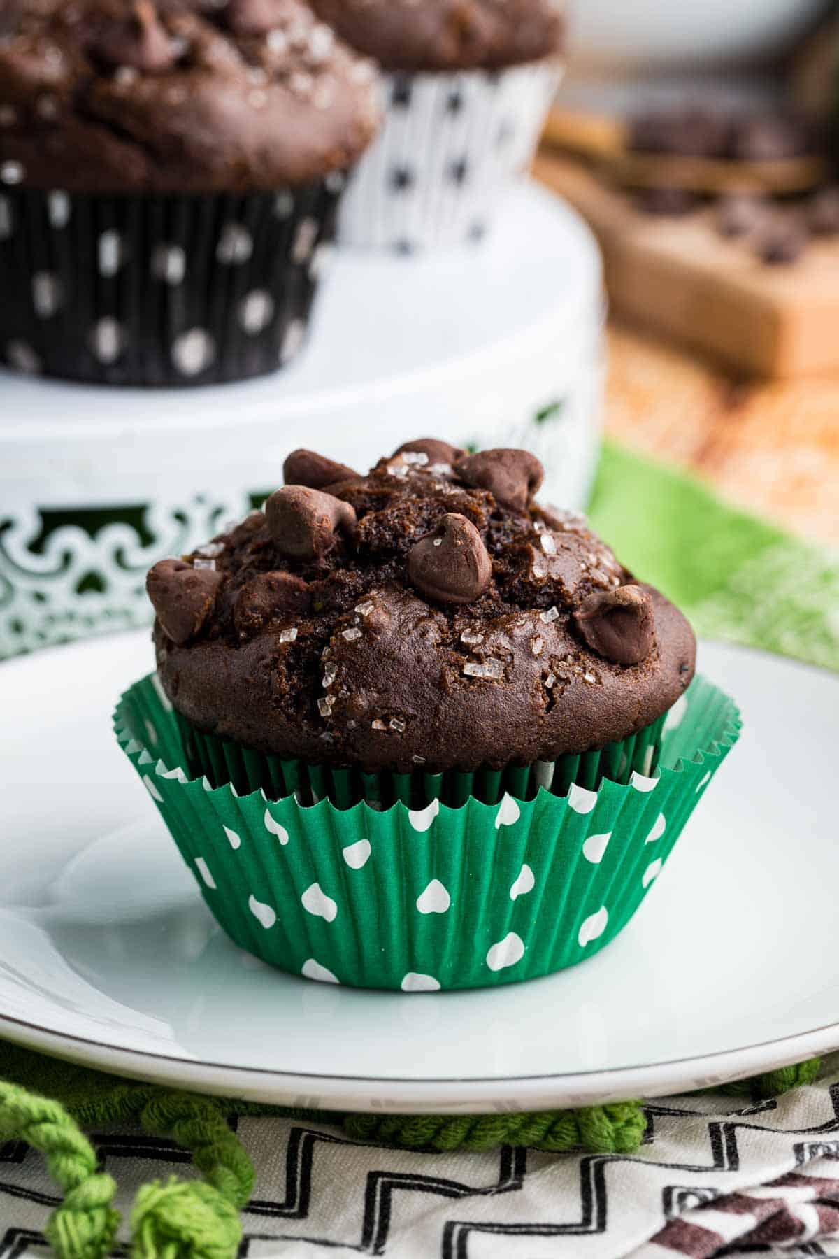 These gluten-free chocolate zucchini muffins are packed with melty chocolate chips and incredibly moist and tender, thanks to the zucchini. Close-up of a gluten free chocolate zucchini muffin on a plate.
