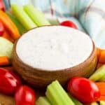 A bowl of Greek yogurt ranch dip surrounded by veggies.