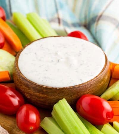 A bowl of Greek yogurt ranch dip surrounded by veggies.