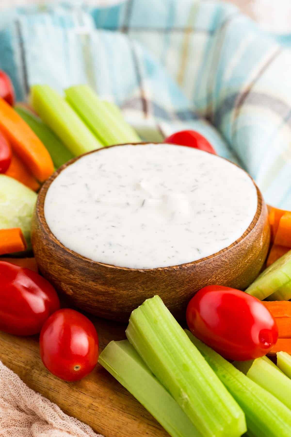 This Greek yogurt ranch dip is full of bold, herby flavors, perfect for scooping up with dippables or spreading it over a juicy burger. A bowl of Greek yogurt ranch dip surrounded by veggies.