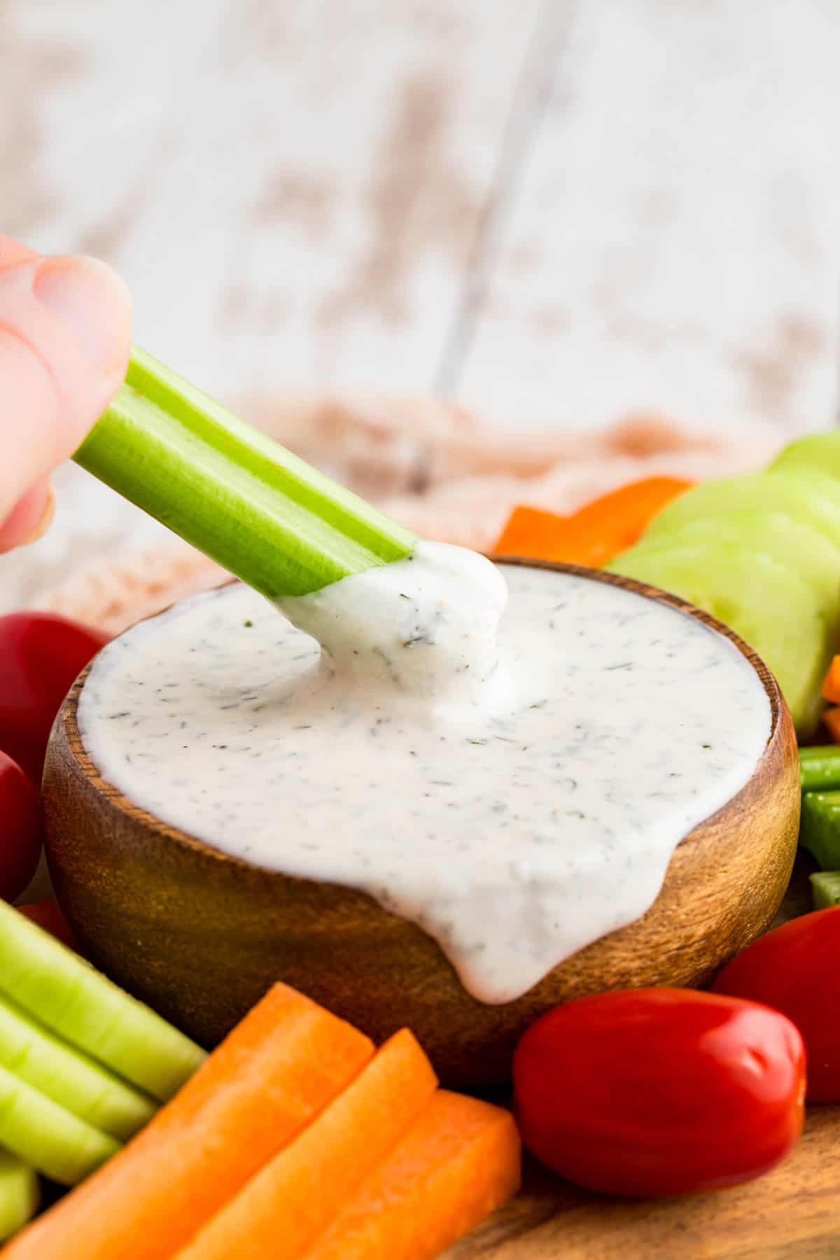 This Greek yogurt ranch dip is full of bold, herby flavors, perfect for scooping up with dippables or spreading it over a juicy burger. Dipping celery into Greek yogurt ranch dip.