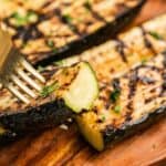 A fork picking up a piece of zucchini with grill marks with text overlay that says "Grilled Zucchini".