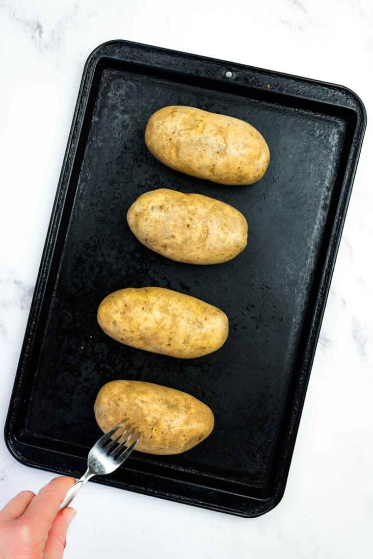Poking Russet potatoes with a fork.