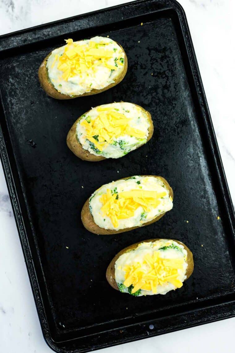 Topping stuffed baked potato shells with extra cheddar cheese.