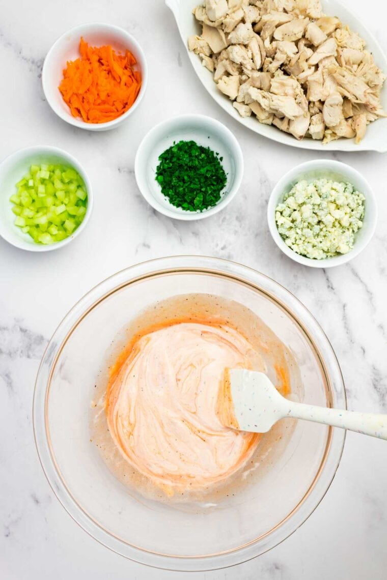 This flavor-packed Buffalo Chicken Salad is made with bold Greek yogurt dressing, tender chicken, crunchy veggies, and blue cheese. Yum! Mixing together yogurt, hot sauce, apple cider vinegar, salt, and pepper to make buffalo dressing.