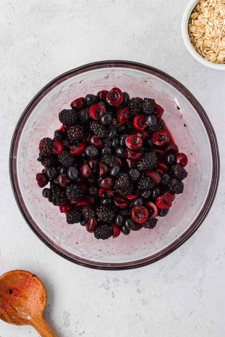 Berries, cornstarch, brown sugar, and lemon juice mixed together in a bowl.