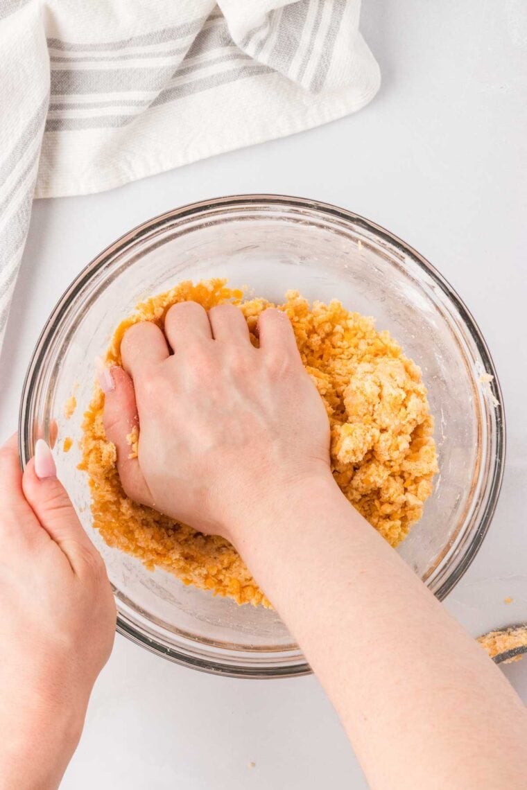 Kneading gluten free cheddar cracker dough in a bowl.
