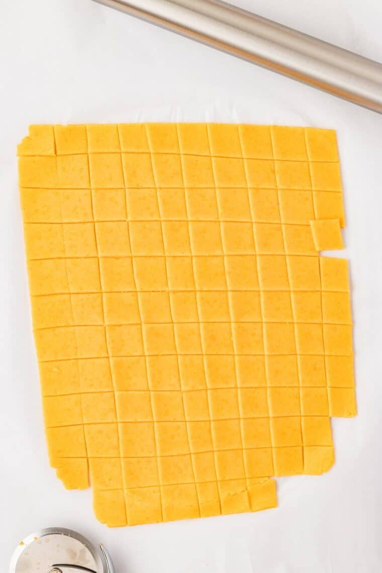 Cutting gluten free cheddar cracker dough into 1-inch squares.