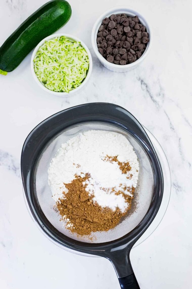 These gluten-free chocolate zucchini muffins are packed with melty chocolate chips and incredibly moist and tender, thanks to the zucchini. Sifting together flour, cocoa powder, leavening agents, and salt.