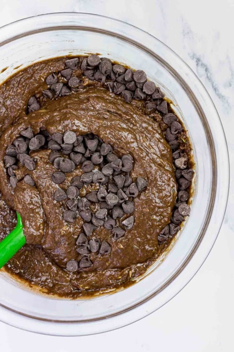 These gluten-free chocolate zucchini muffins are packed with melty chocolate chips and incredibly moist and tender, thanks to the zucchini. Stirring chocolate chips into chocolate zucchini batter.