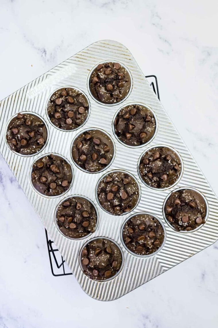 These gluten-free chocolate zucchini muffins are packed with melty chocolate chips and incredibly moist and tender, thanks to the zucchini. GF chocolate zucchini muffins cooling in a pan.