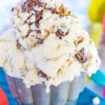 Scoops of ice cream with pieces of puppy chow snack mix in it with text overlay that says "No-Churn Puppy Chow Ice Cream".