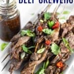 A platter of steak on a stick garnished with cilantro and red chili peppers with text overlay that says "Teriyaki Beef Skewers".