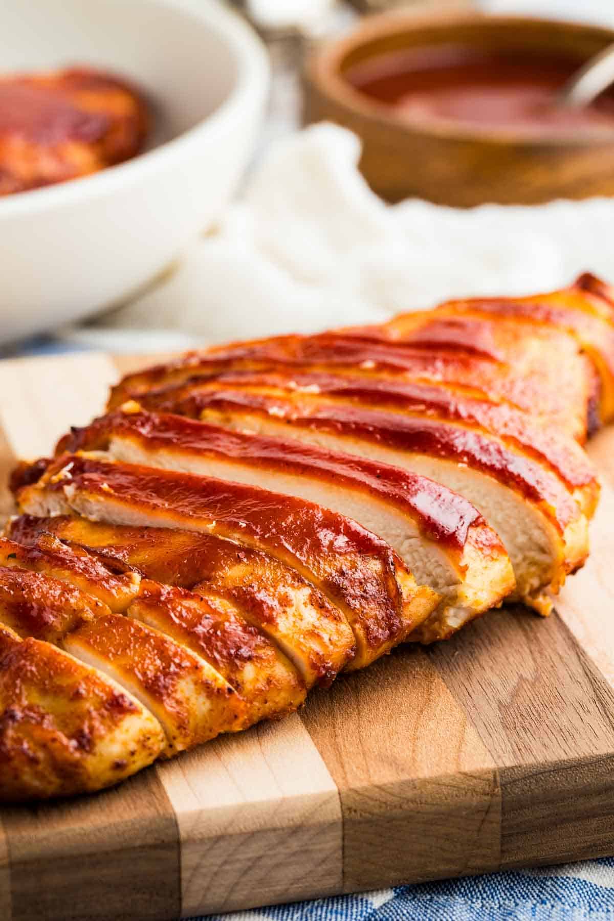 Close-up image of a sliced air fryer BBQ chicken breast on a cutting board.