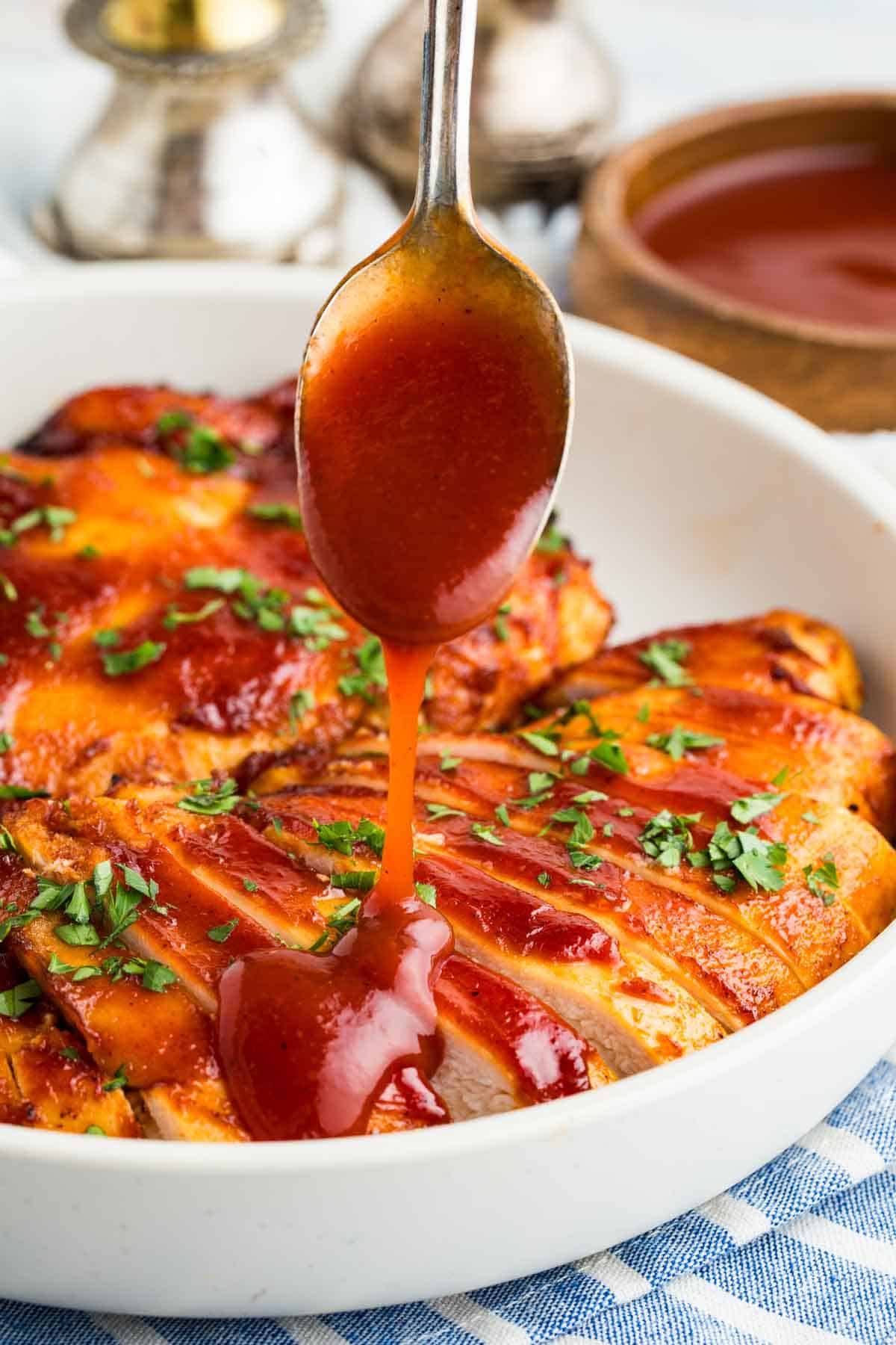 Drizzling BBQ chicken with BBQ sauce.