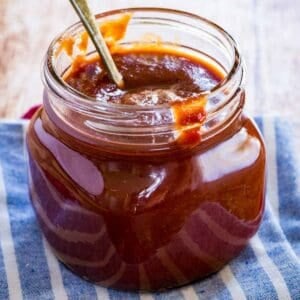 A spoon in a glass jar of barbecue sauce.