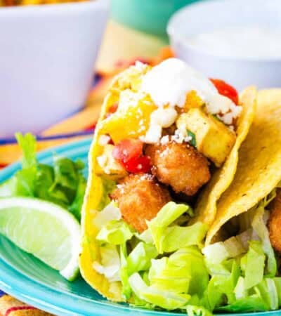 A fish stick taco with mango salsa on a blue plate.