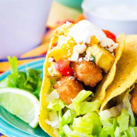 A fish stick taco with mango salsa on a blue plate.