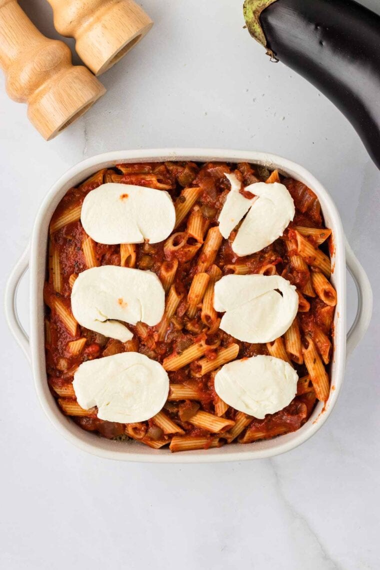 Adding a second layer of sliced mozzarella to eggplant casserole.