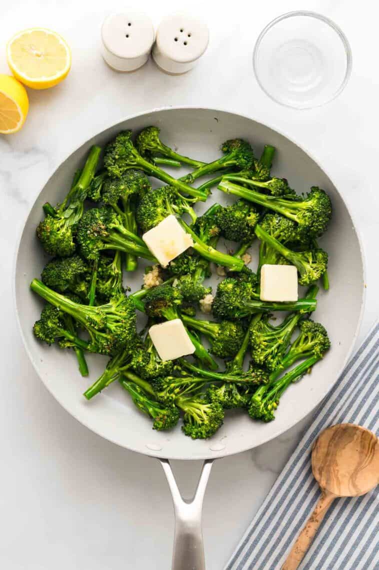Adding butter, garlic, and lemon juice to a pan of sauteed broccolini.
