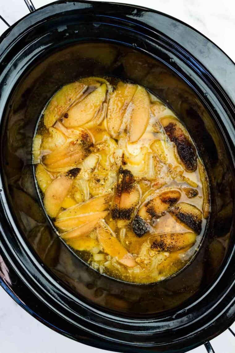 This easy slow cooker pulled chicken is simmered for hours with hard apple cider, apples, and onion. It's SO tender and ideal for sandwiches! Slow cooker apple cider chicken in a crockpot, ready to be shredded.