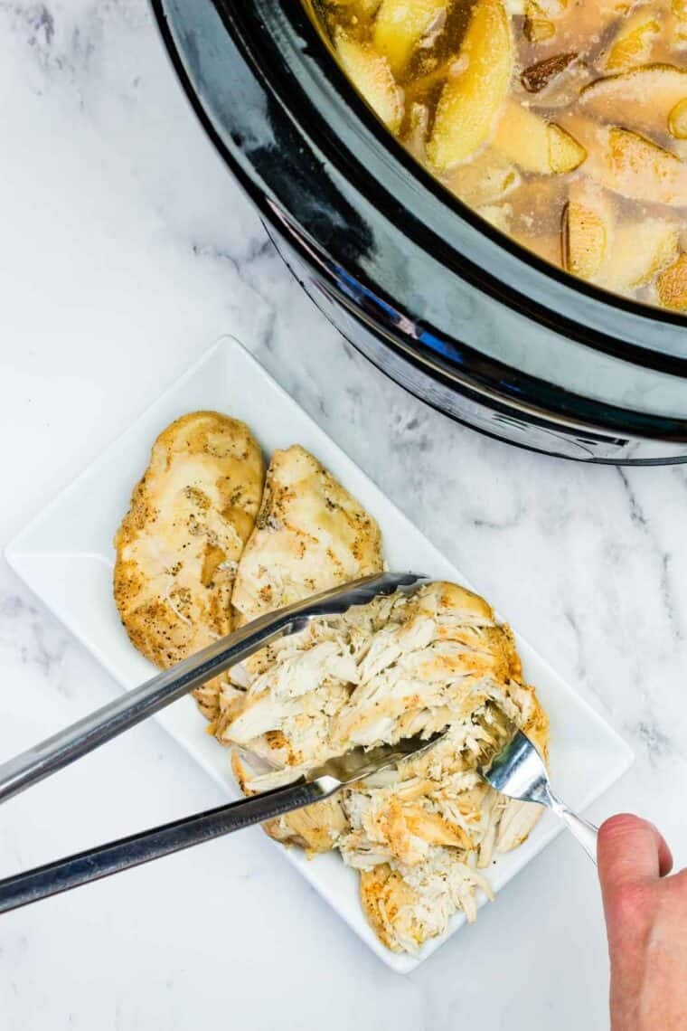 This easy slow cooker pulled chicken is simmered for hours with hard apple cider, apples, and onion. It's SO tender and ideal for sandwiches! Shredding slow cooker apple cider chicken.