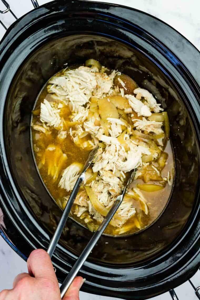 This easy slow cooker pulled chicken is simmered for hours with hard apple cider, apples, and onion. It's SO tender and ideal for sandwiches! Tossing pulled chicken with its cooking juices (along with the apples, onions, and seasonings it cooked with).