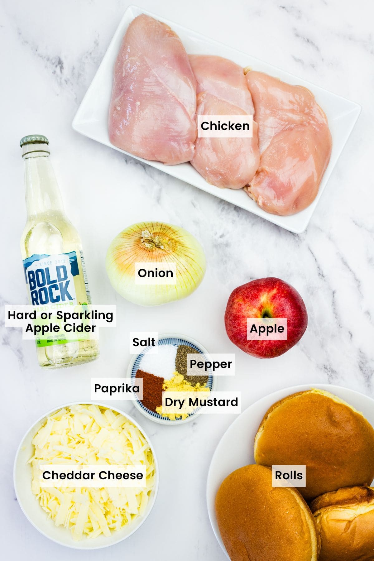 This easy slow cooker pulled chicken is simmered for hours with hard apple cider, apples, and onion. It's SO tender and ideal for sandwiches! Labeled ingredients for slow cooker apple cider pulled chicken.