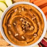 Overhead image of sweet potato hummus topped with maple syrup and walnuts, surrounded by dippables.