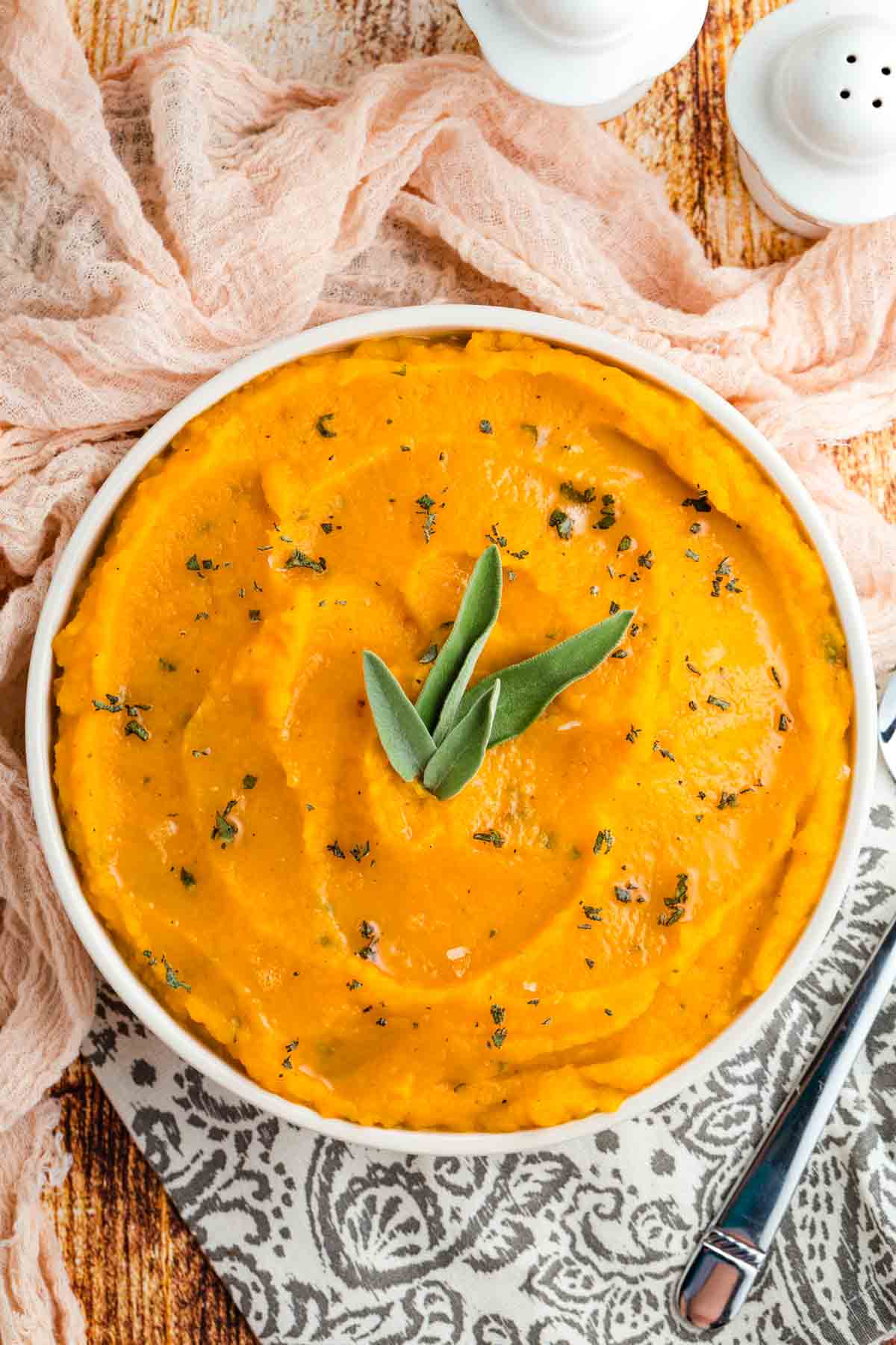 Overhead image of mashed butternut squash in a serving bowl, garnished with fresh sage leaves.