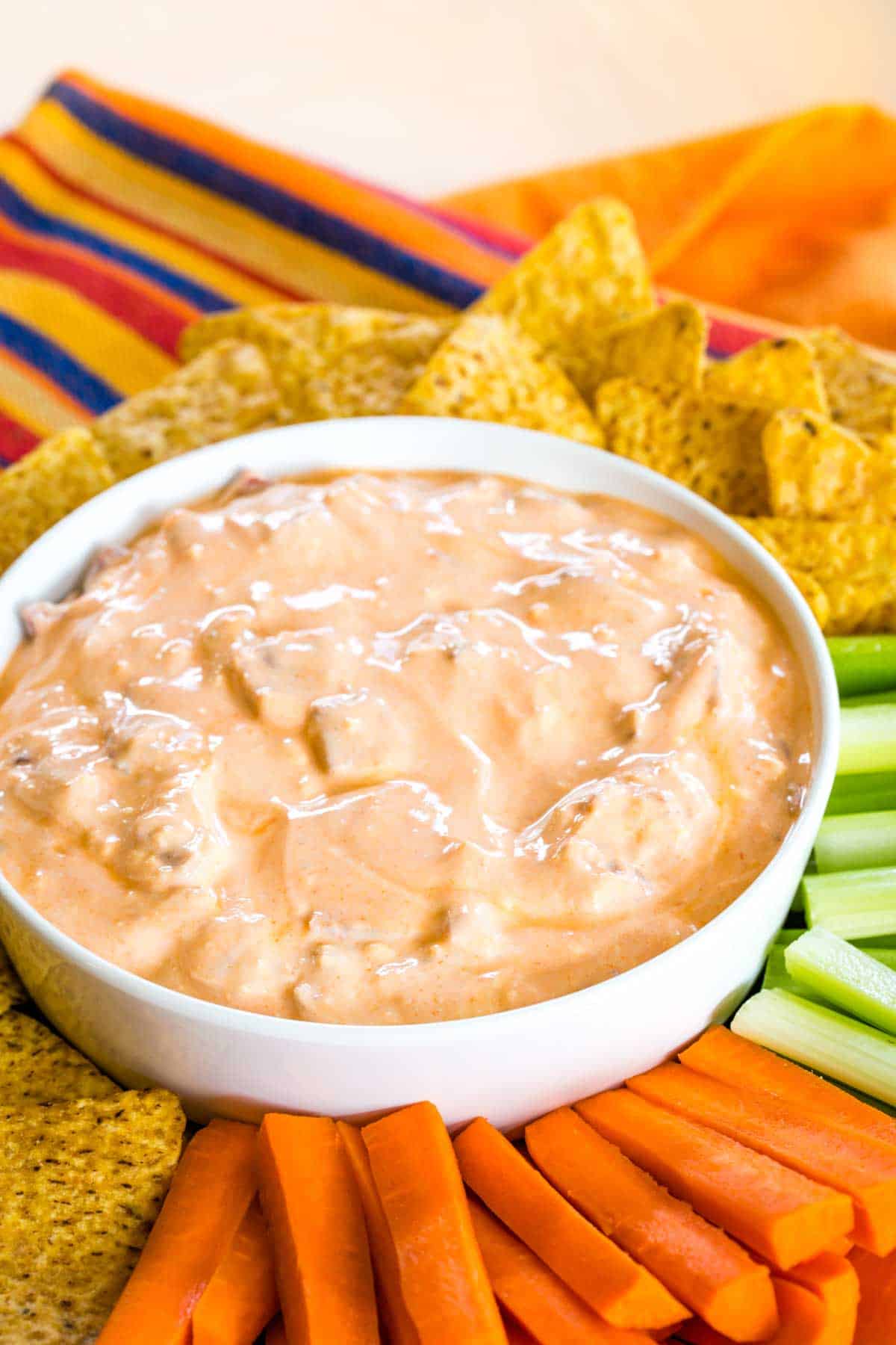 Bacon Buffalo blue cheese dip in a bowl surrounded by veggies and chips.