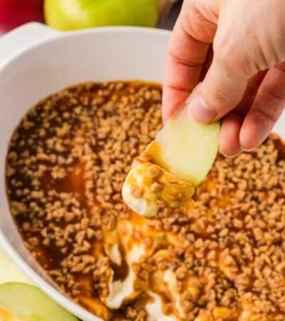 Scooping up caramel apple dip with an apple slice.