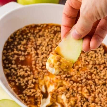 Scooping up caramel apple dip with an apple slice.