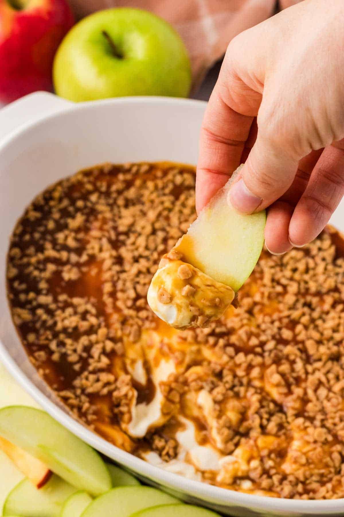 Scooping up caramel apple dip with an apple slice.
