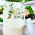 Sherry vinaigrette in a mason jar with dressed salads behind it.