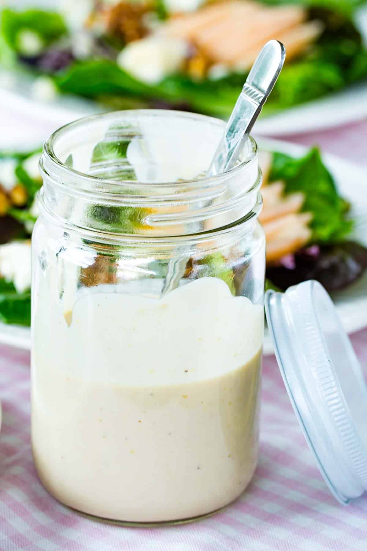 Sherry vinaigrette in a mason jar with dressed salads behind it.